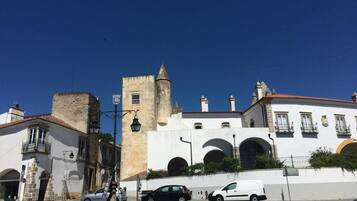 Une rue bordée de bâtiments historiques, dont une tour et des arcades.