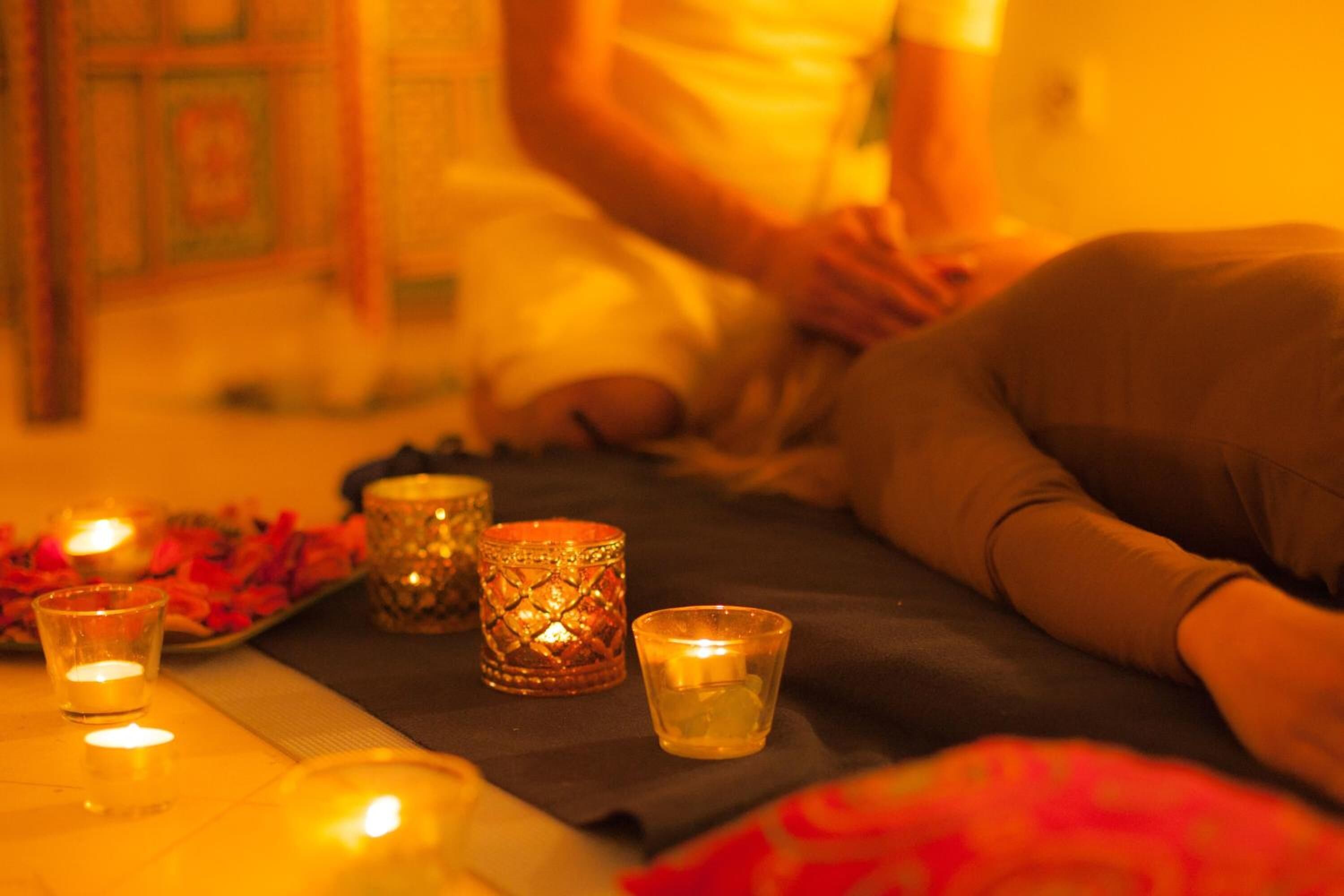 Una persona acostada en una cama con velas y una bandeja de flores.