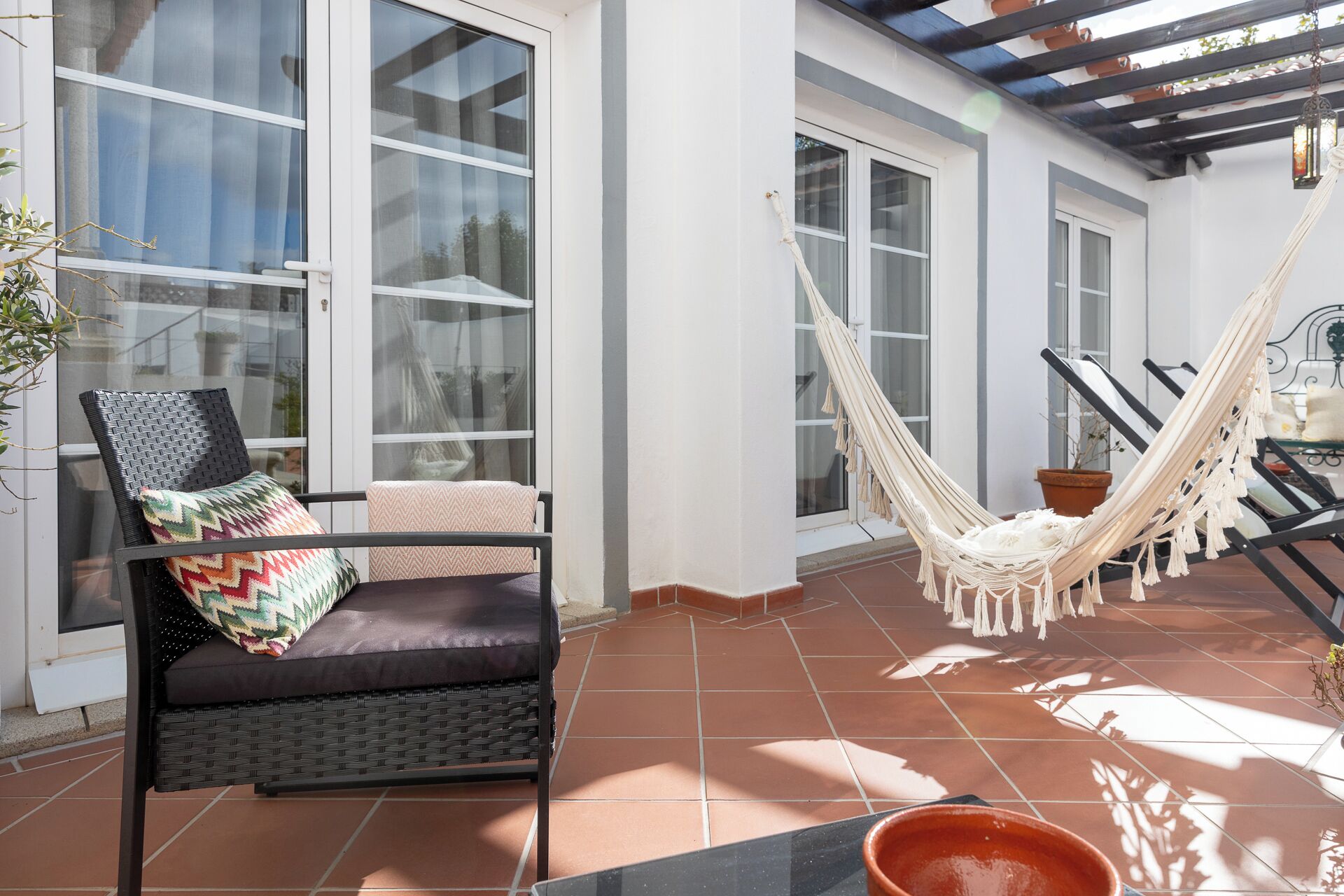 Un patio con una silla de mimbre, una hamaca y una planta en maceta.