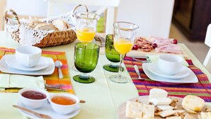 A breakfast table set with various food items, including fruits, cheeses, and bread, along with cups and glasses. - Casa Do Platano (Arraiolos)
