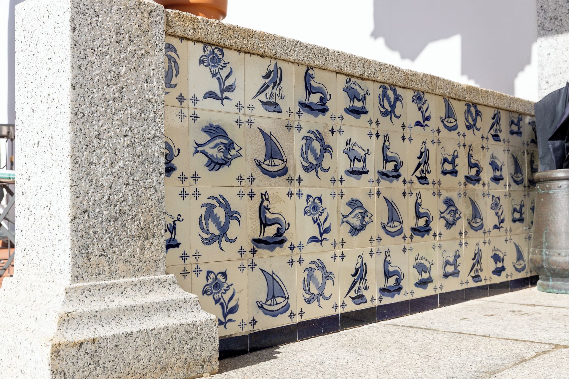 A tiled wall with blue and white patterns, including fish, flowers, and other designs.