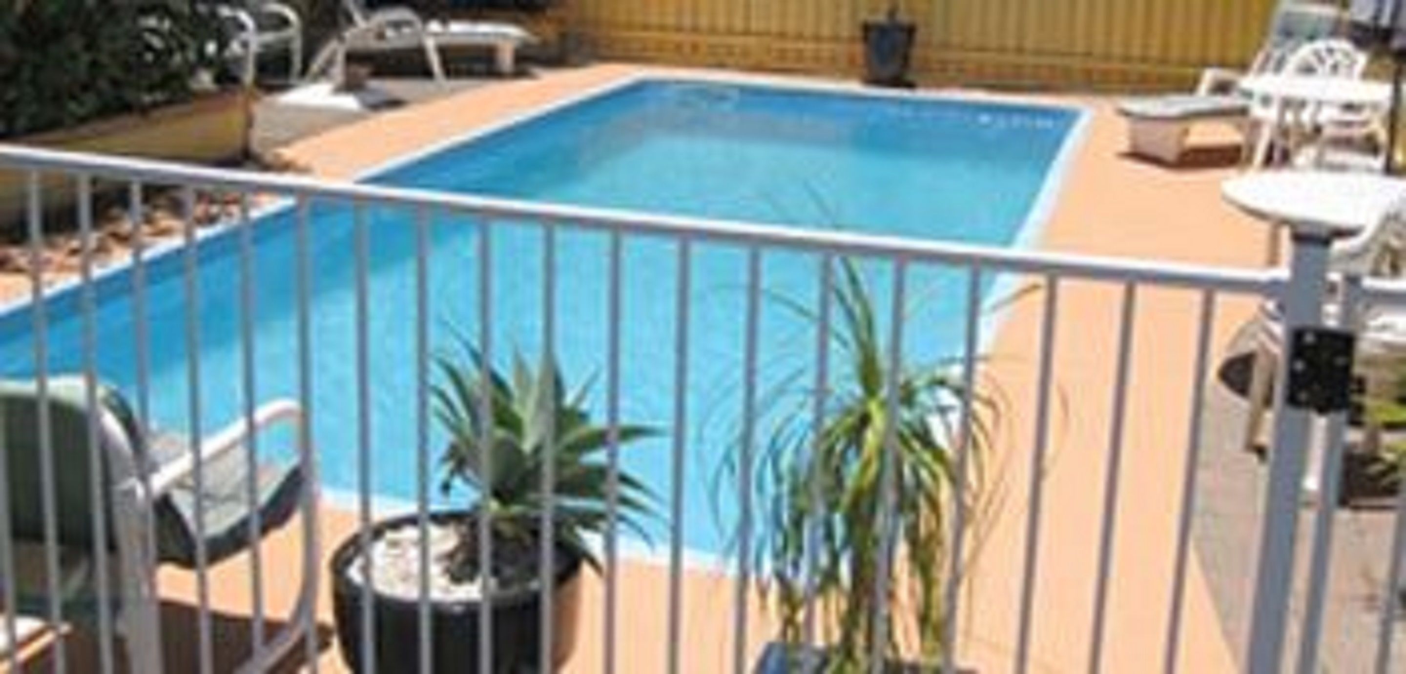 A rectangular swimming pool with a white fence surrounding it.