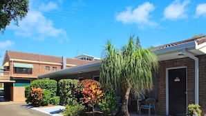 Un edificio con fachada de ladrillo, un patio cubierto y un pequeño árbol en la parte delantera.