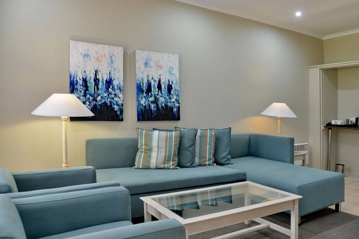 A modern living room with a sofa, two lamps, and abstract wall art.