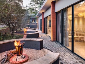 A modern outdoor patio with built-in fire pits and a glass door leading to a seating area.