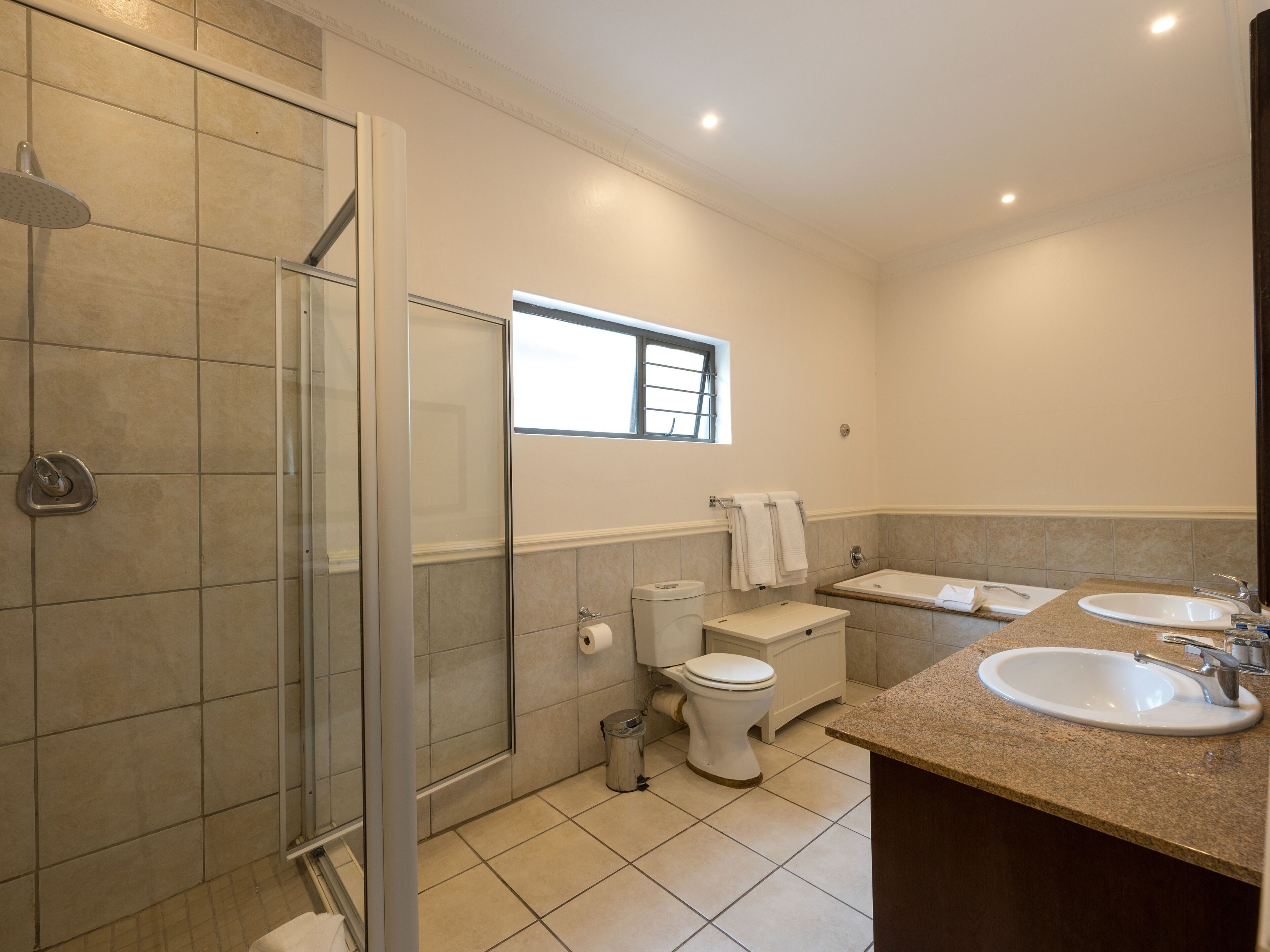 A bathroom with a shower, toilet, sink, and window.
