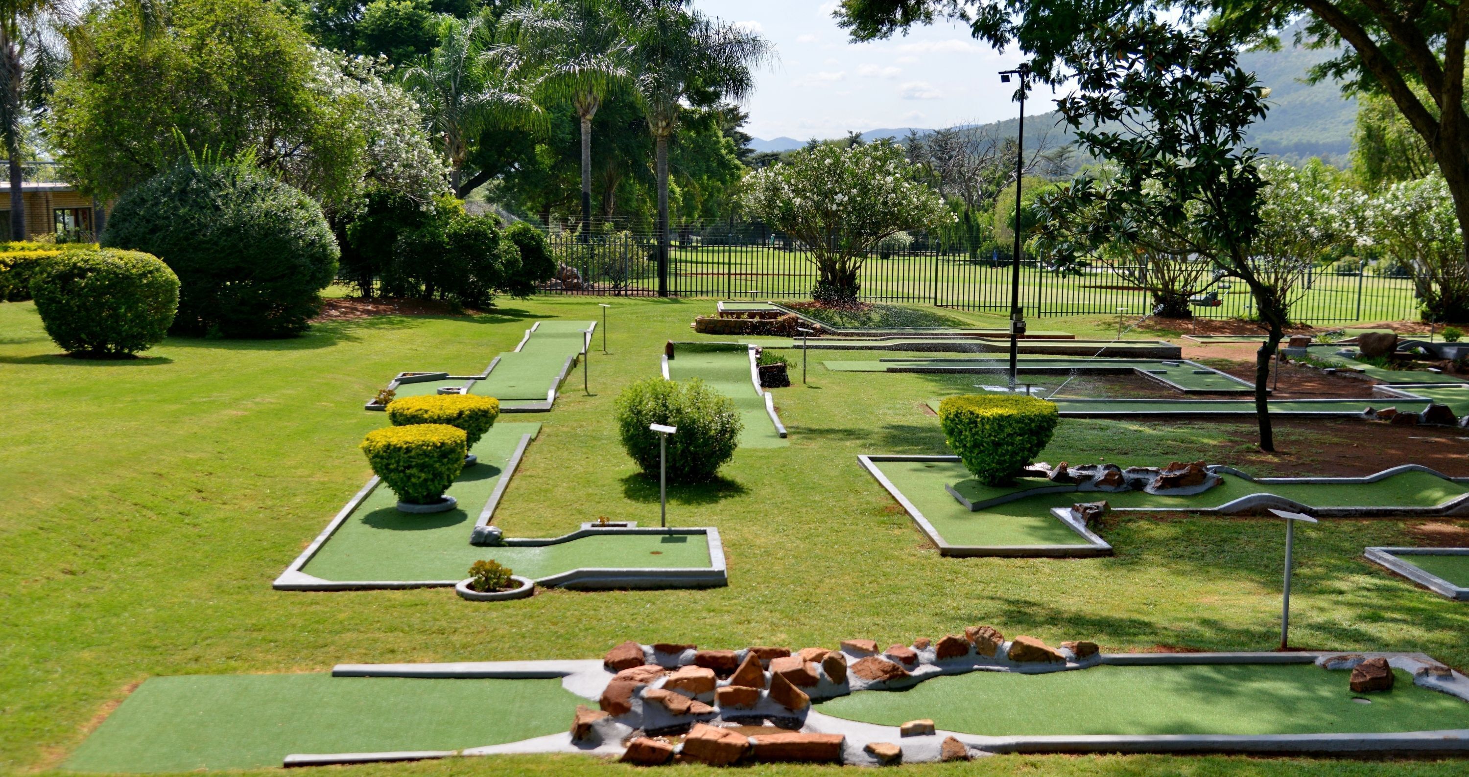A miniature golf course with multiple holes, surrounded by well-manicured lawns and trees.