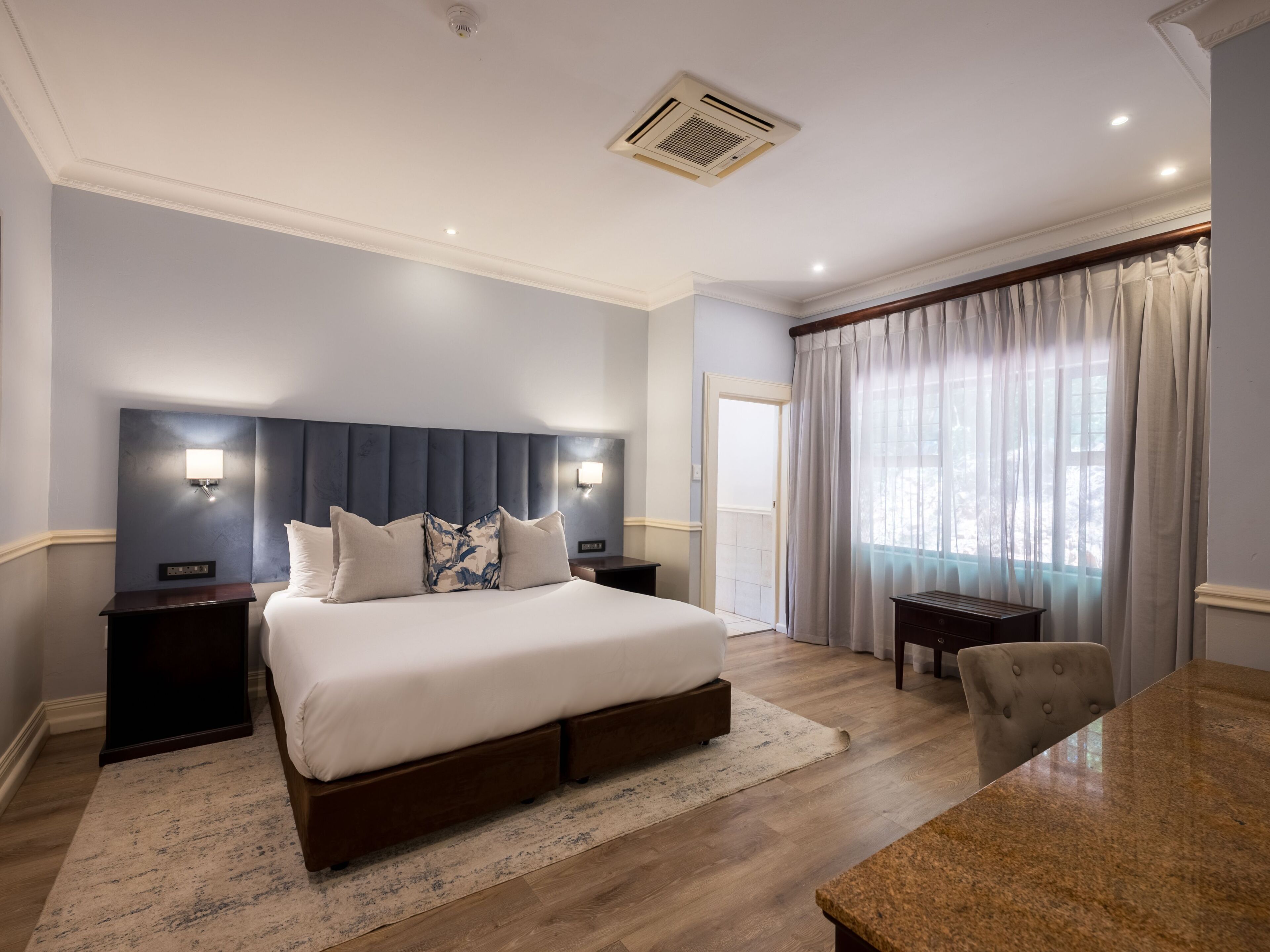 Une chambre d’hôtel avec un grand lit, deux tables de chevet, un bureau et une chaise.