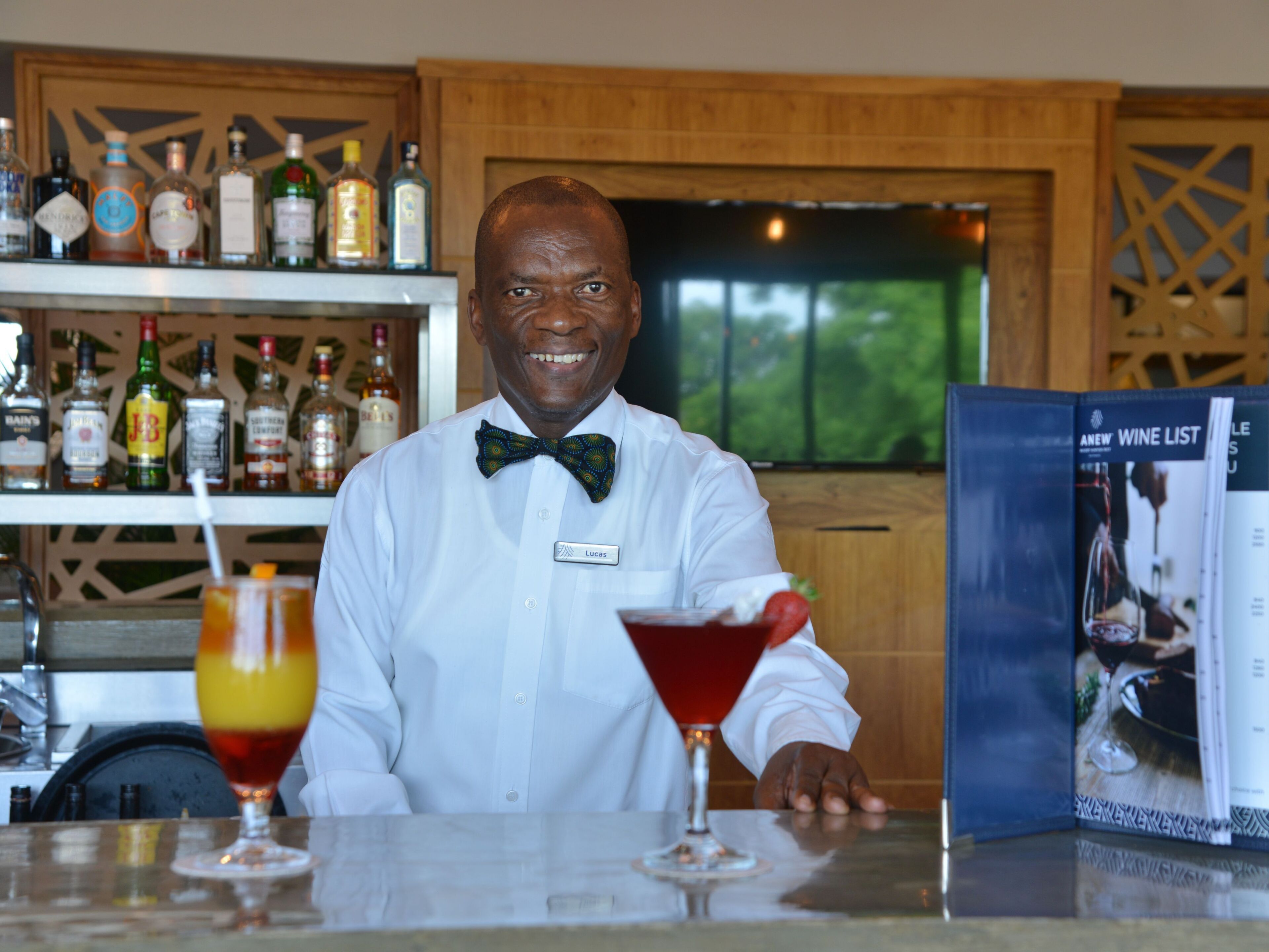 A bar area with a bartender, a selection of liquor bottles, a martini glass, and a wine list.