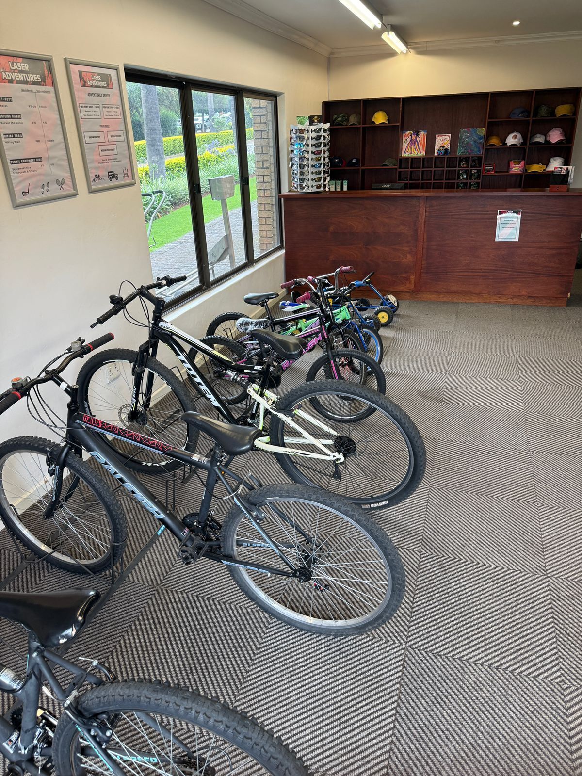 A room with bicycles parked against the wall, a reception desk, and a bulletin board with various notices.