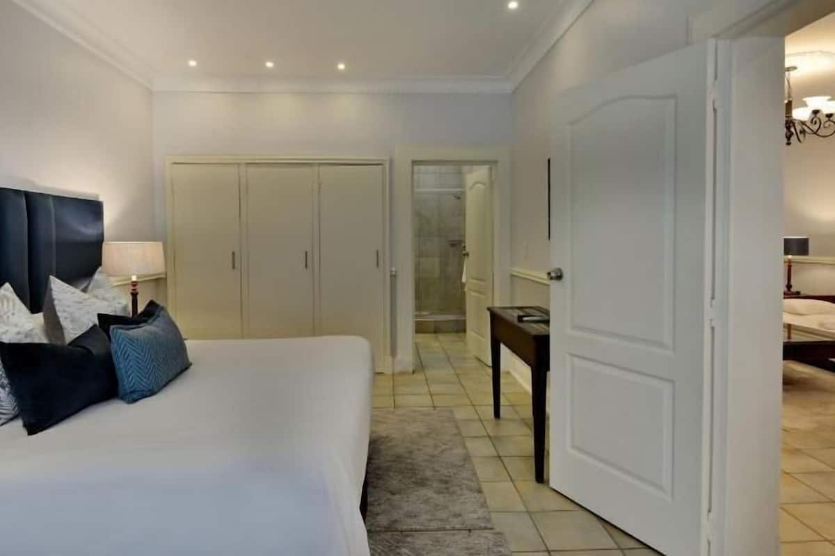 A hotel room with a bed, a desk, a wardrobe, and a shower area.