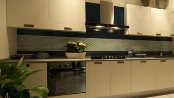 Una cocina moderna con armarios blancos, una campana extractora de acero inoxidable y un salpicadero con diseño.
