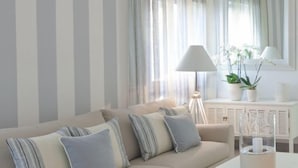 A modern living room with a beige sofa, striped pillows, a white coffee table, and a lamp.