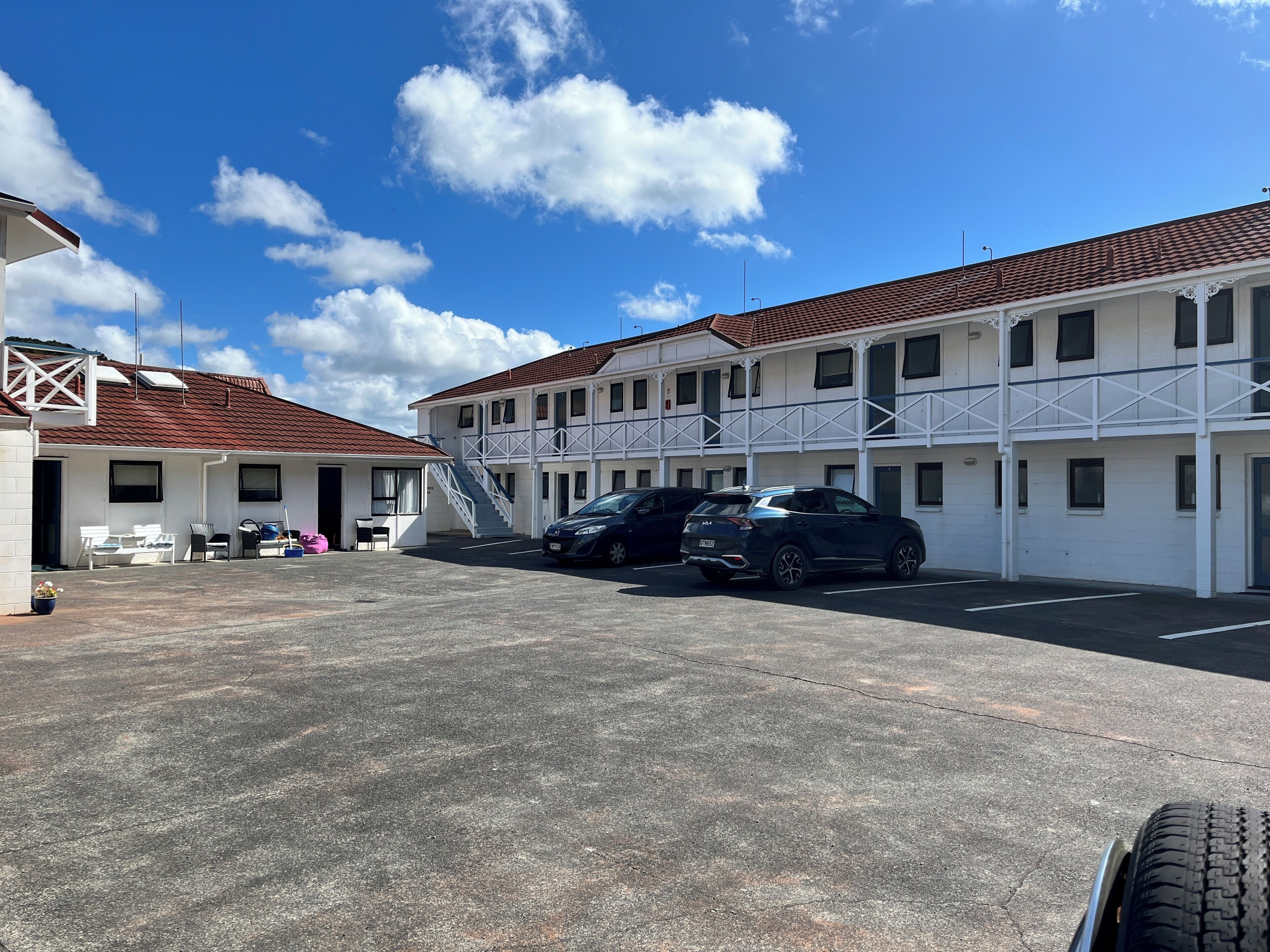 A motel with a two-story structure, a covered parking area, and a staircase leading to the upper level.