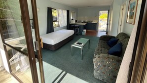 Una habitación compacta con cama, pequeña kitchenette, sofá y zona de comedor.