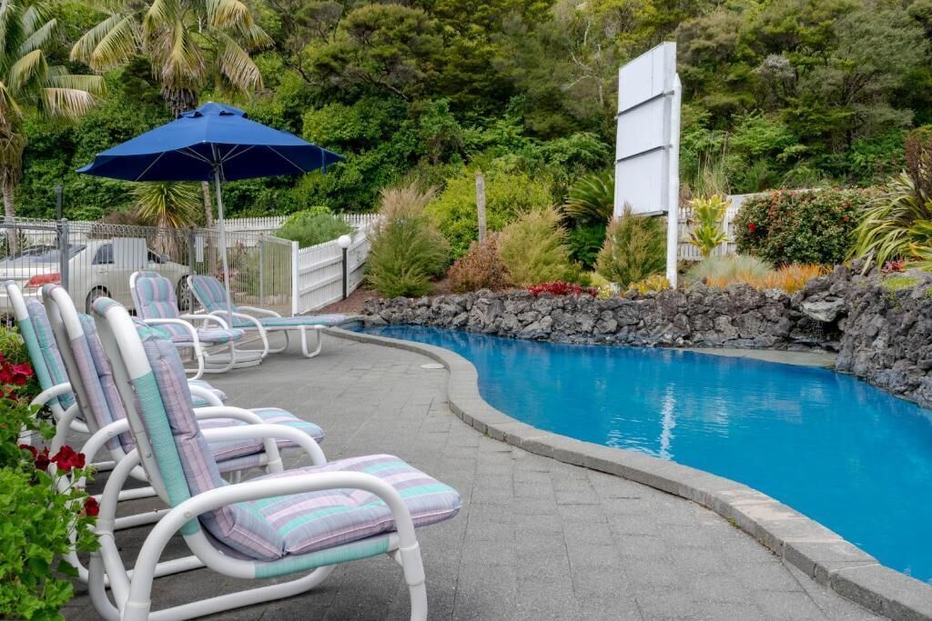 Un área de piscina con sillas de descanso y una sombrilla azul.