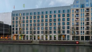A modern hotel with a stone facade, multiple floors, and a waterfront view. - Aparthotel Kiel (Kiel)