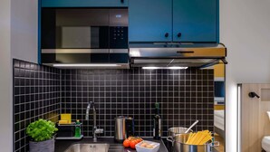 A modern kitchen with a stainless steel sink, a microwave, and a pot of spaghetti on the counter. - Aparthotel Kiel (Kiel)
