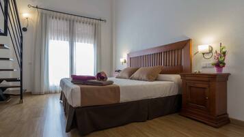 A bedroom with a bed, bedside table, lamp, and a view of a staircase.