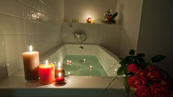 A bathtub with candles and a bouquet of roses.