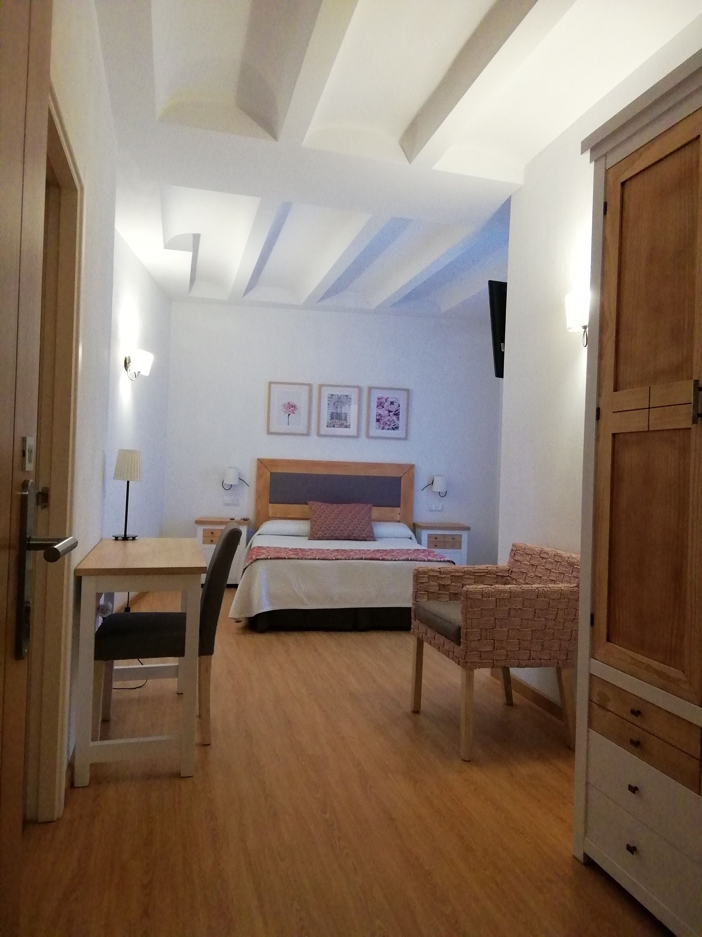 Un dormitorio con cama, mesitas de noche, escritorio, silla y armario.