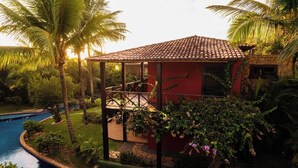 A red building with a tiled roof, a balcony, and a pool. - Domus Villas de Luxo (Tibau do Sul)