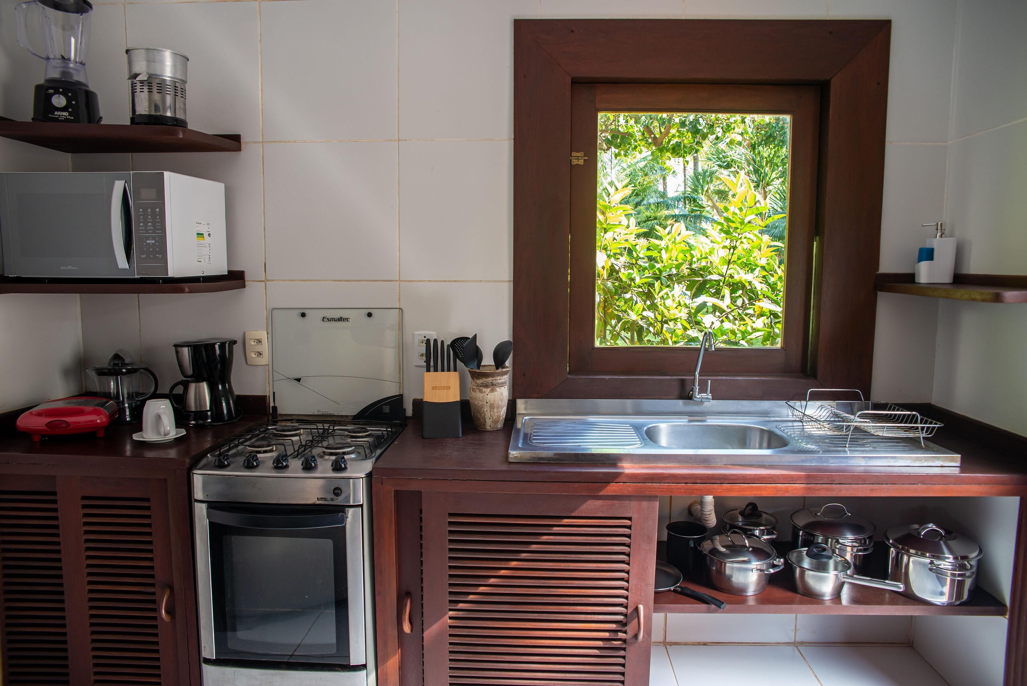 A compact kitchen with a gas stove, microwave, and a window with a view of greenery.