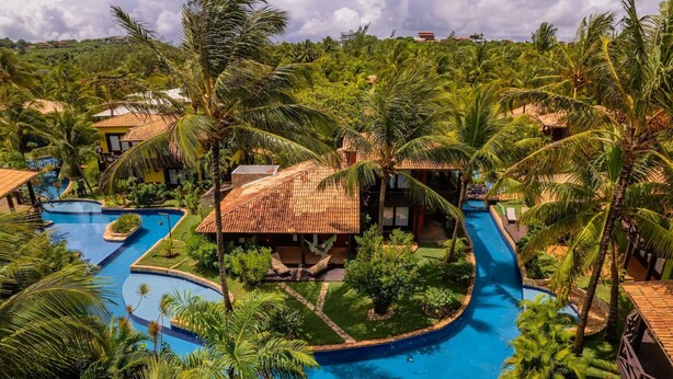 A resort with multiple swimming pools, palm trees, and a central building with a tiled roof. - Domus Villas de Luxo (Tibau do Sul)