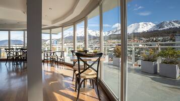 A modern interior with large windows offering a view of a snowy mountain and a town below.