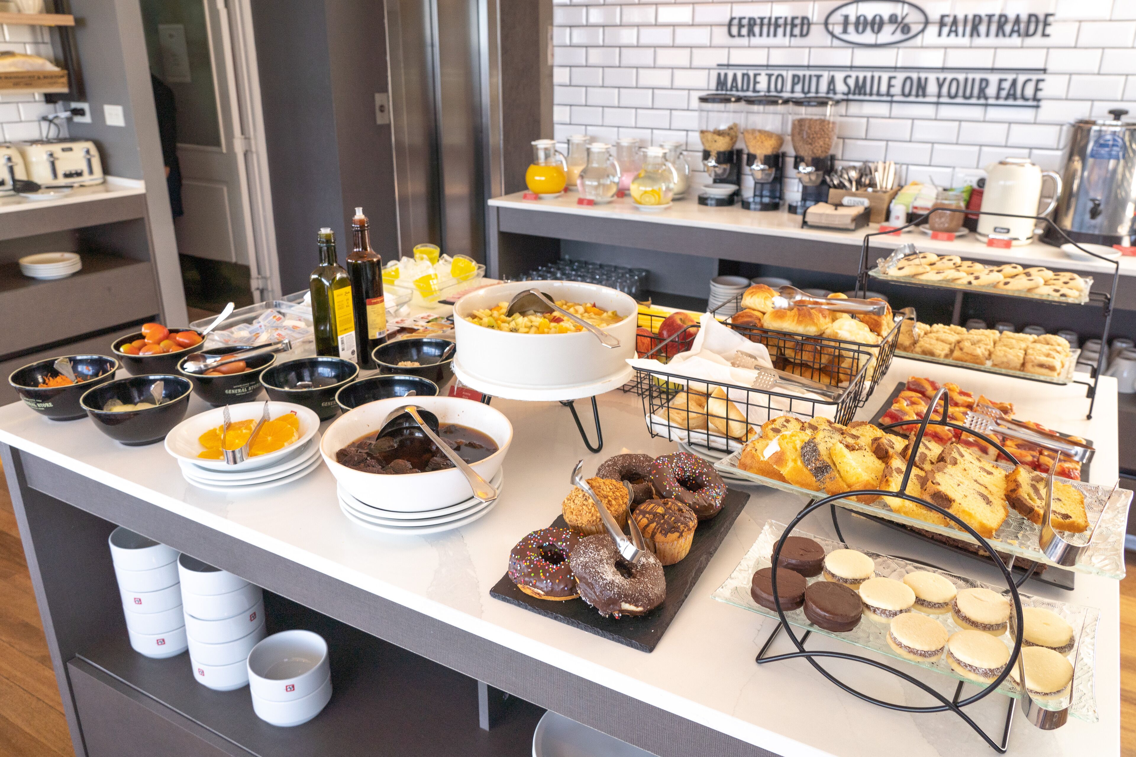 A buffet with various food items including bowls of cereal, pastries, and desserts.