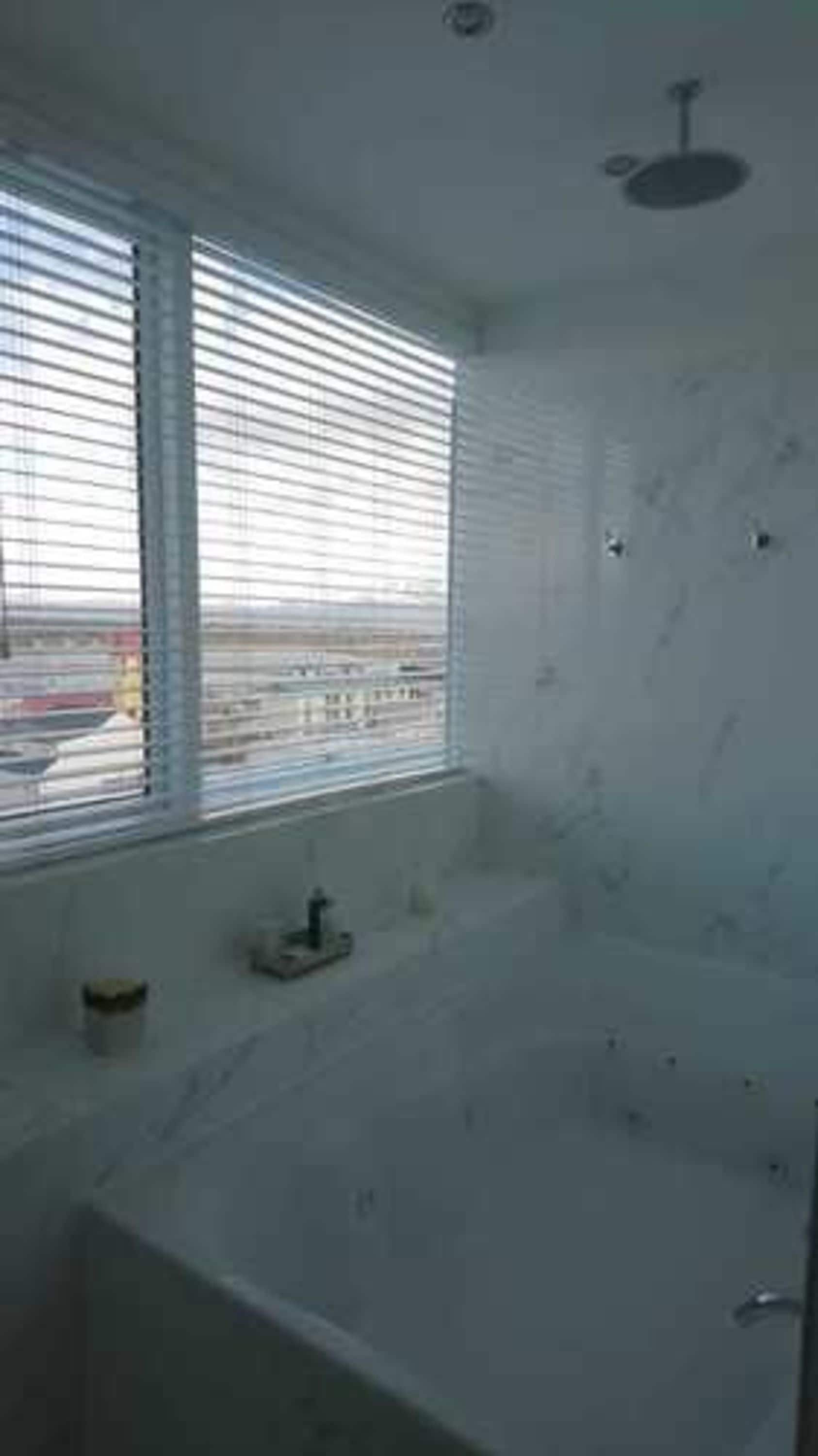 A bathroom with a large window, a bathtub, and a shower area.