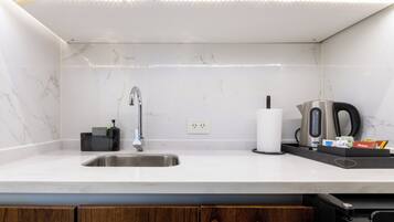 A modern kitchen with a stainless steel sink, a marble backsplash, and wooden cabinets.