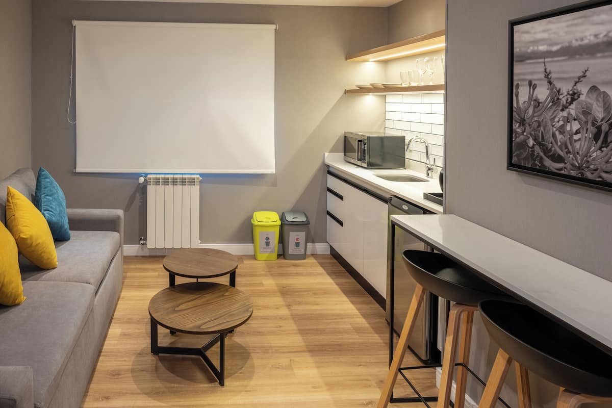 A compact living space with a sofa, a small round table, a kitchenette, and a dining area.