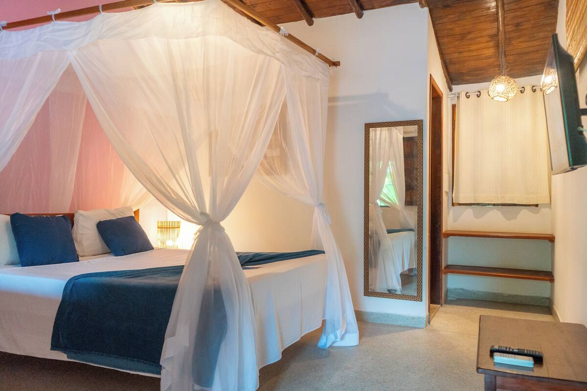 Ein Schlafzimmer mit einem Himmelbett, einem Nachttisch, einem Spiegel und einer Hängelampe.