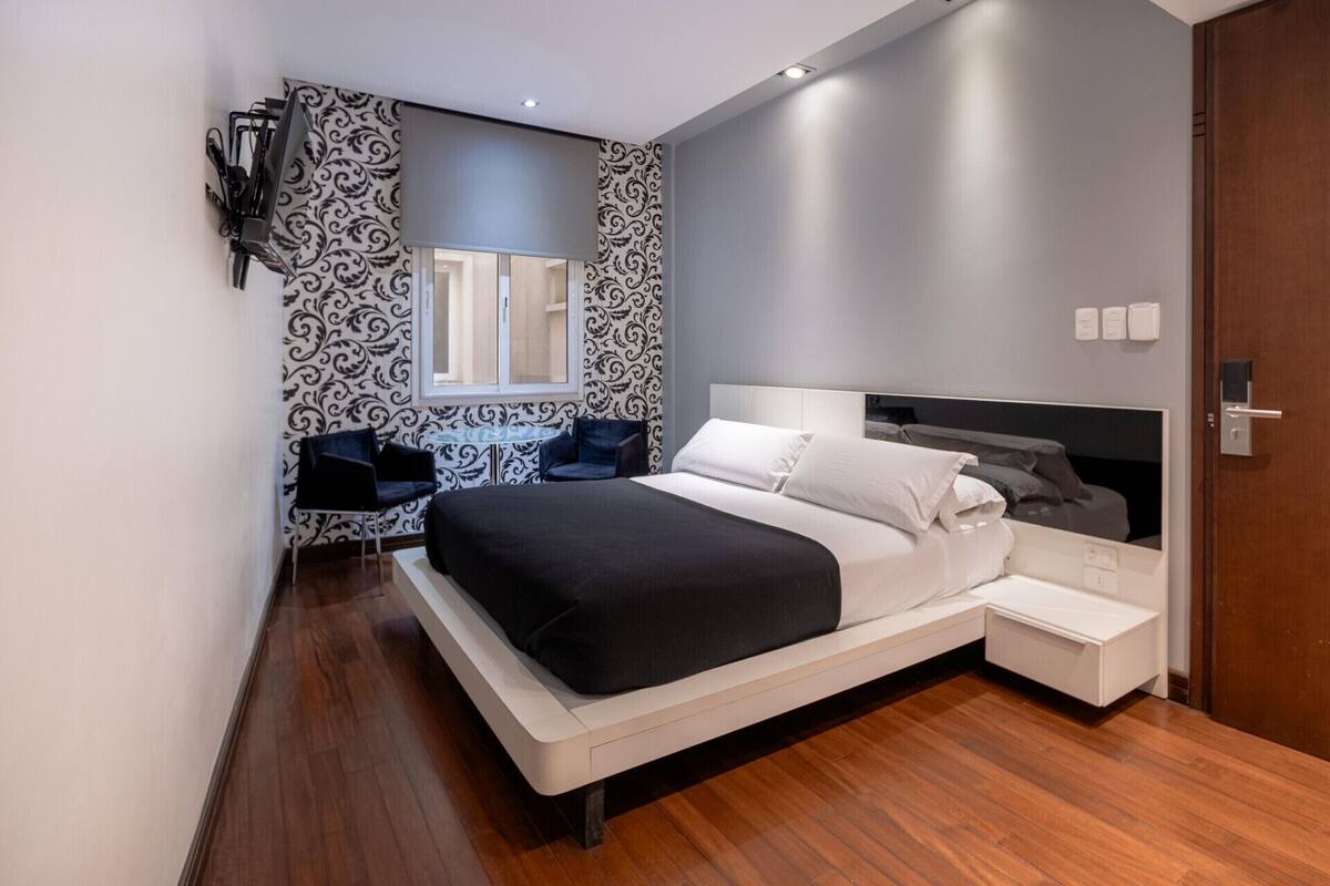 A modern bedroom with a large bed, bedside tables, a desk, and a chair.