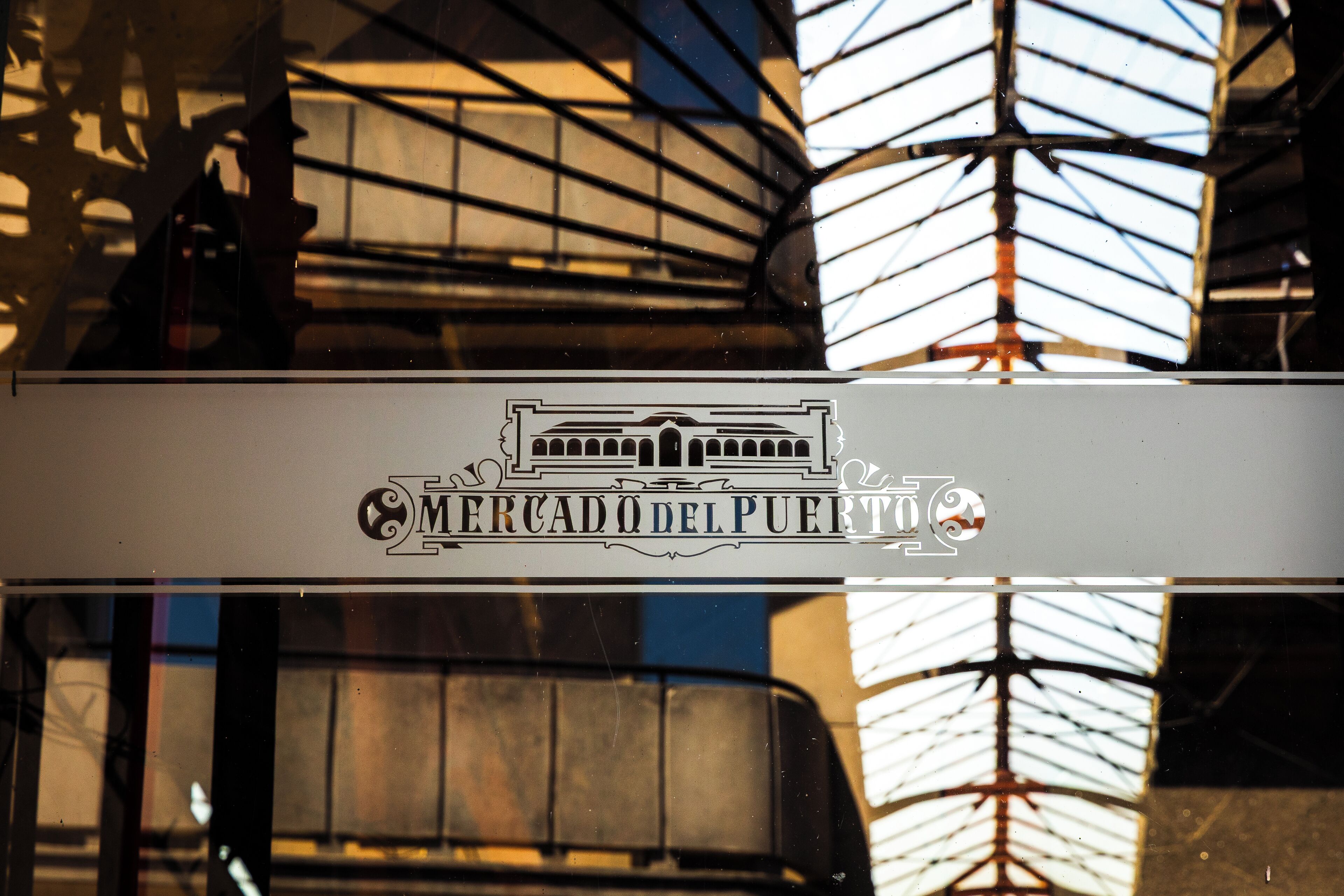 A building facade with a reflective glass surface and a sign reading "Mercado del Puerto".