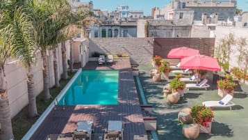 Een buitenzwembad, ligstoelen bij het zwembad