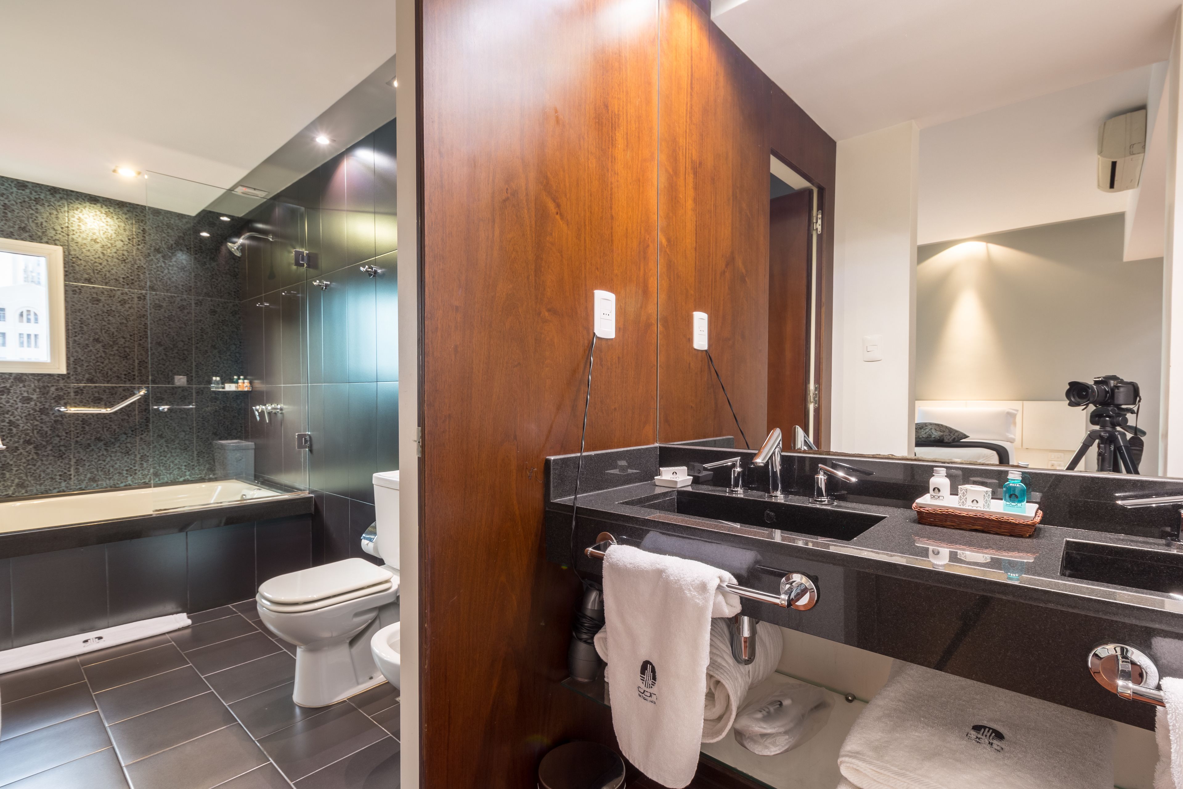 Une salle de bain moderne avec un meuble-lavabo en bois, une cabine de douche en verre et des toilettes séparées.