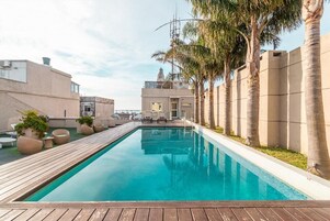 Una piscina al aire libre, sillones reclinables de piscina