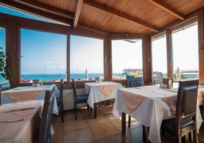A restaurant with tables and chairs, large windows with a view of the sea, and a wooden ceiling. - Mevlana Boutique Hotel (Istanbul)