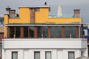 A building with a yellow upper section and a white lower section, featuring large windows and a balcony with flowers. - Mevlana Boutique Hotel (Istanbul)