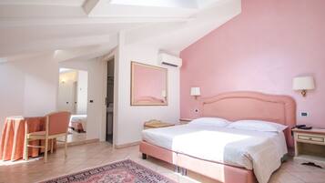 Un dormitorio con pared rosa, una cama, un escritorio y una silla.