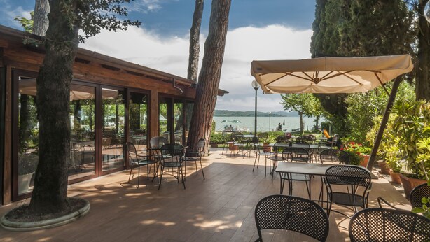 Un patio al aire libre con mesas y sillas, con vista a un cuerpo de agua.