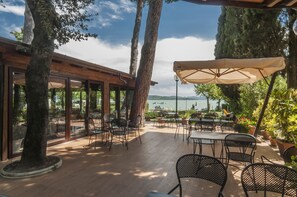 Un patio al aire libre con mesas y sillas, con vista a un cuerpo de agua.