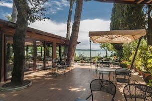 An outdoor patio with tables and chairs, overlooking a body of water.
