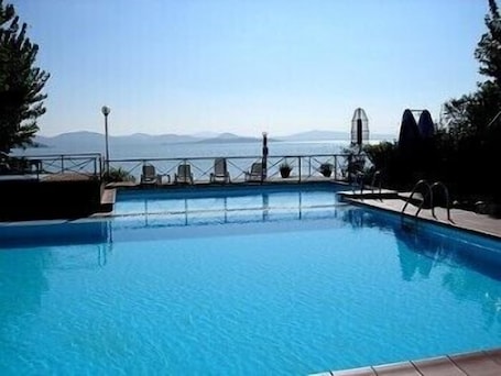 Una piscina al aire libre, sillones reclinables de piscina