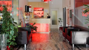 A modern lobby with a marble floor, seating areas, and a kitchen visible in the background. - Hotel Firenze (San Michele al Tagliamento)