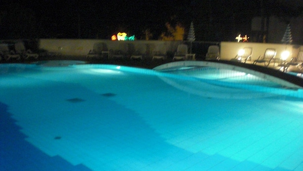 A swimming pool with a tiled edge and a few lounge chairs around it. - Hotel Firenze (San Michele al Tagliamento)