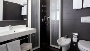 A modern bathroom with a glass-enclosed shower, a white sink, a bidet, and a toilet. - Hotel Firenze (San Michele al Tagliamento)