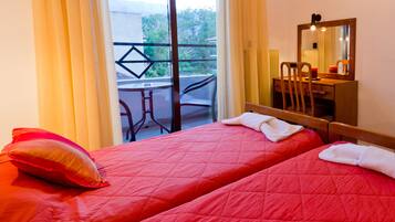 Habitación de hotel con dos camas, un escritorio y una silla. Cuenta con un balcón con mesa y sillas.